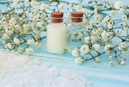 Magnesium lotion and magnesium oil in small corked bottles surrounded with flowers.